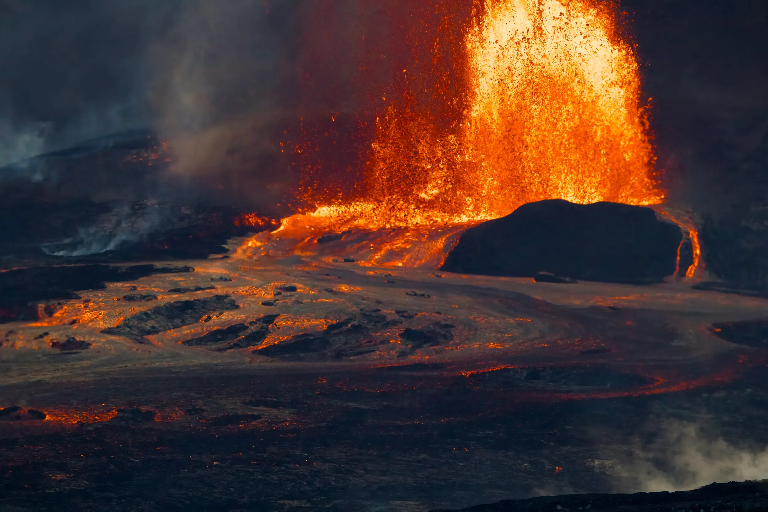Lava erupting in Hawaii Volcanoes National Park, an incandescent orange fountain against dark rock